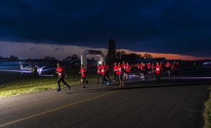 Renners van de Runway Run die in de schemering over de landingsbaan van vliegveld Teuge rennen.